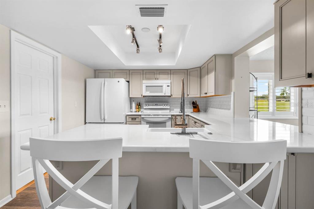 A kitchen features white countertops, light-colored cabinets, stainless steel appliances, and a breakfast bar — 1226 HADDINGTON CIRCLE, SUN CITY CENTER, FL