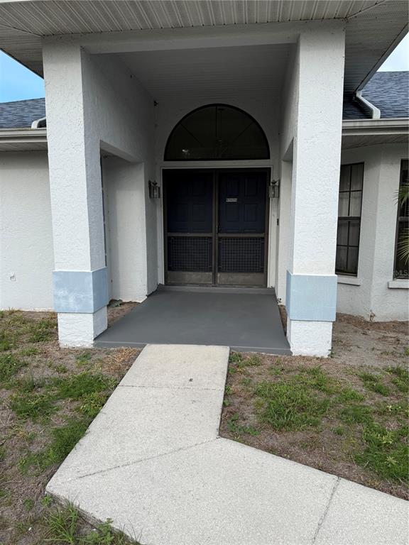 A concrete walkway leads to a covered entryway with two dark doors and a transom window — 4675 32ND COURT E, BRADENTON, FL