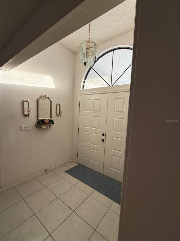 An entryway features a tiled floor, a double door with an arched window, and a chandelier — 4675 32ND COURT E, BRADENTON, FL