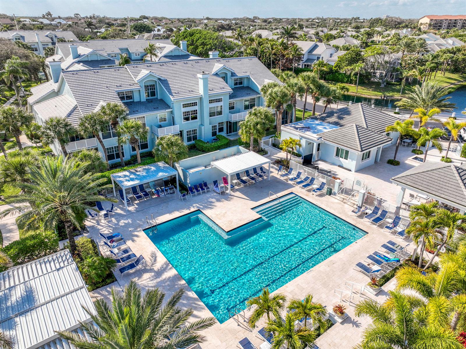 An aerial view shows a light blue multi-story building with a large L-shaped swimming pool — 3004 Mainsail Circle, Jupiter FL 33477, JUPITER, FL