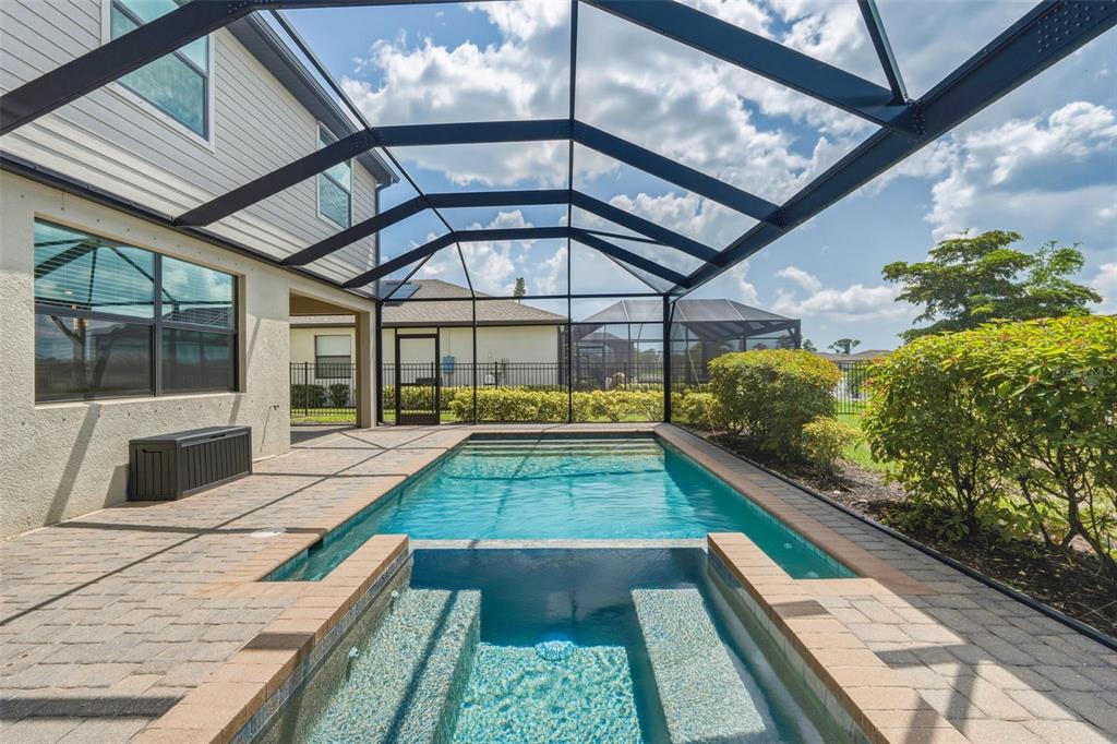 A screened-in patio features a swimming pool and an attached spa with paver decking — 1824 E ISLES ROAD, PORT CHARLOTTE, FL