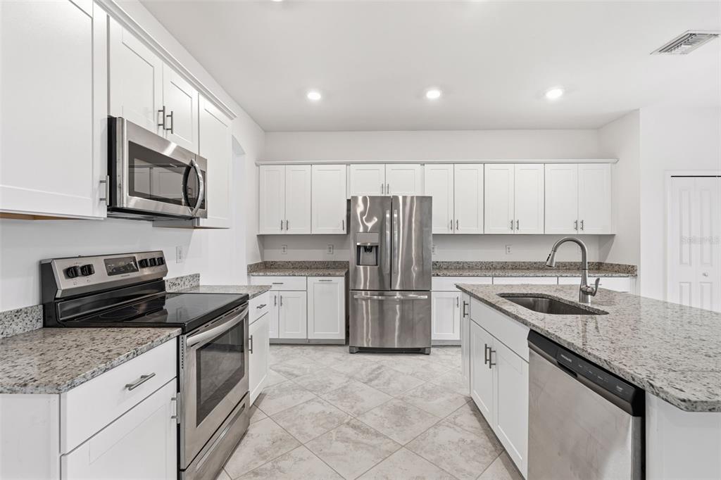 A modern kitchen features white cabinets, stainless steel appliances, and granite countertops — 1824 E ISLES ROAD, PORT CHARLOTTE, FL