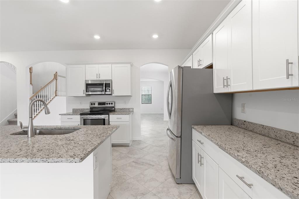 A kitchen features white cabinets, granite countertops, stainless steel appliances, and a central island — 1824 E ISLES ROAD, PORT CHARLOTTE, FL