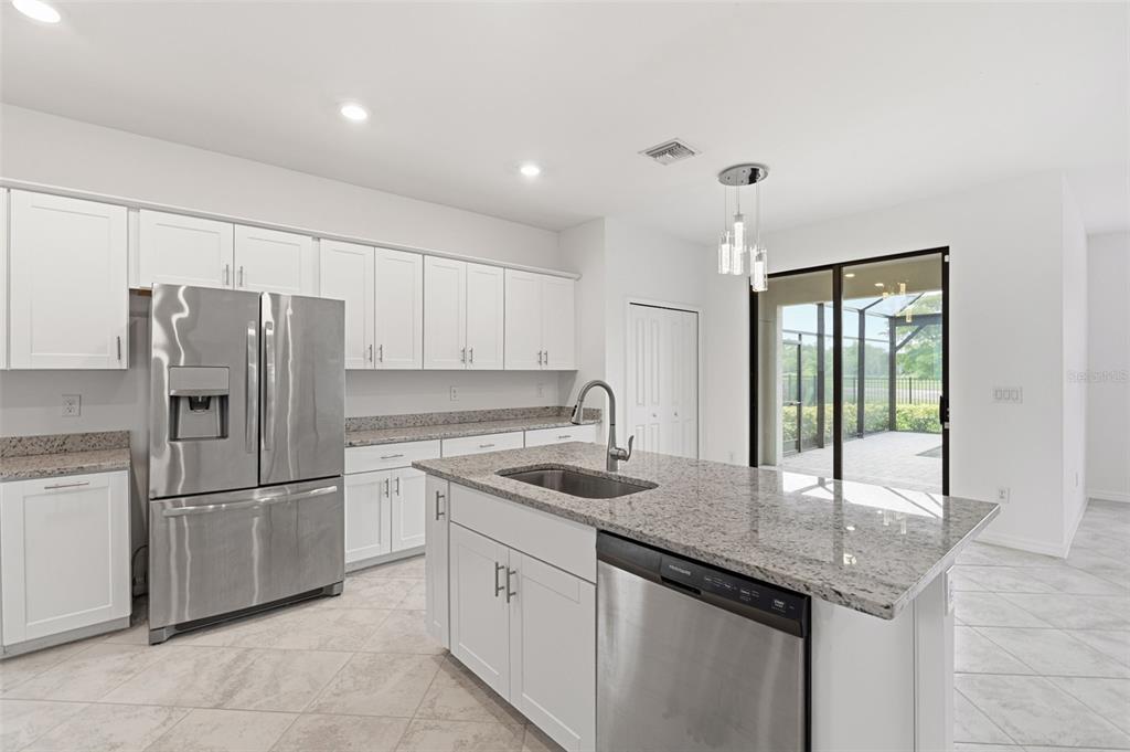 A modern kitchen features white cabinets, granite countertops, stainless steel appliances, and a center island — 1824 E ISLES ROAD, PORT CHARLOTTE, FL