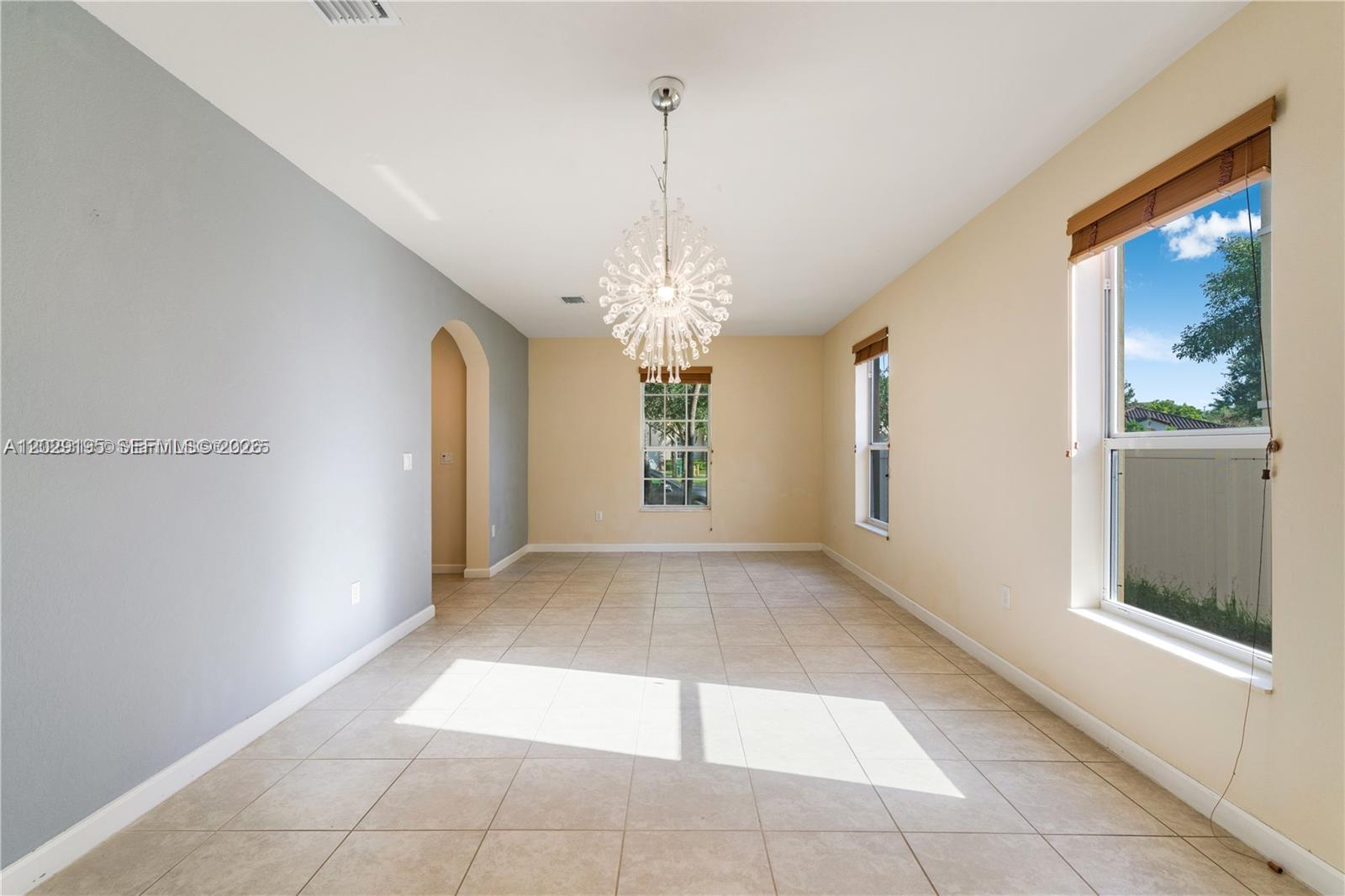 A dining room features tiled floors, a sputnik chandelier, and walls painted in two colors — 16946 SW 90th Terrace Circle, Miami FL 33196, MIAMI, FL