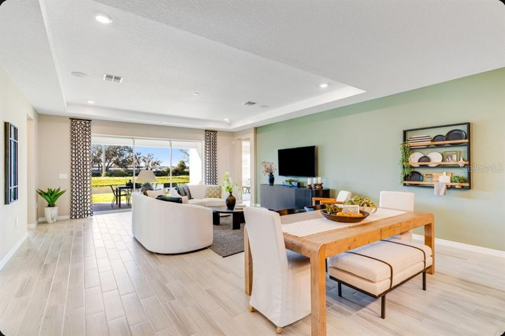An open-concept living and dining area features light tile floors, a green accent wall, and sliding doors — 903 LADYFISH TRAIL, ST CLOUD, FL