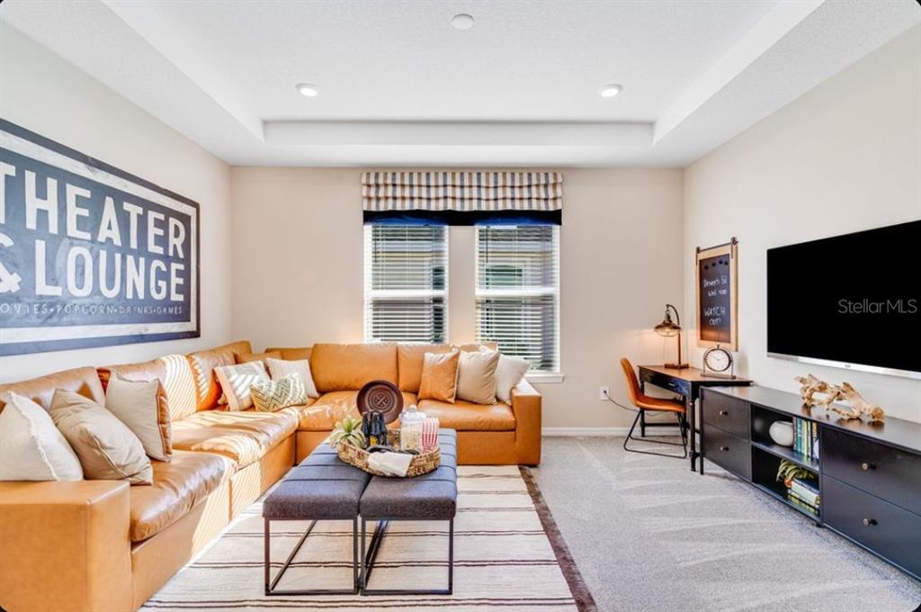 A living room features a tan leather sectional, a dark media console, and a desk — 903 LADYFISH TRAIL, ST CLOUD, FL