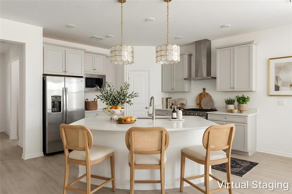 A modern kitchen features light gray cabinets, a curved white island, and three rattan barstools — 19689 FORT KING RUN, BROOKSVILLE, FL