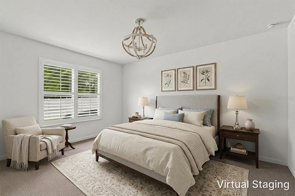 A bedroom with a bed, armchair, nightstands, and a chandelier features virtual staging — 19689 FORT KING RUN, BROOKSVILLE, FL