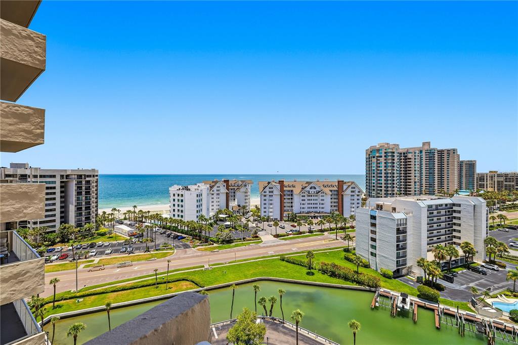 An elevated view of a coastal resort area featuring high-rise buildings, a canal, and ocean — 1621 GULF BOULEVARD UNIT 1408, CLEARWATER BEACH, FL