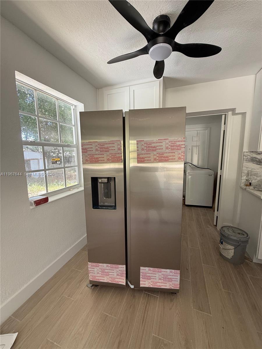 A stainless steel refrigerator stands in a kitchen with light wood-look tile flooring — 5264 NE 15th Ave, Pompano Beach FL 33064, POMPANO BEACH, FL