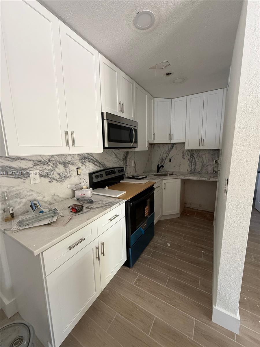 A kitchen features white shaker cabinets, marble-patterned countertops, and a stainless steel microwave — 5264 NE 15th Ave, Pompano Beach FL 33064, POMPANO BEACH, FL