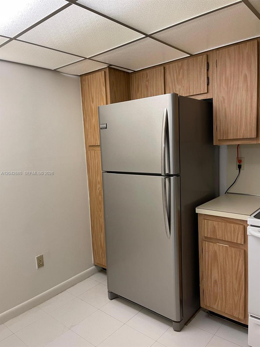 A kitchen features a stainless steel refrigerator, wood cabinets, and a drop ceiling — 20840 San Simeon Way # 308, Miami FL 33179, MIAMI, FL