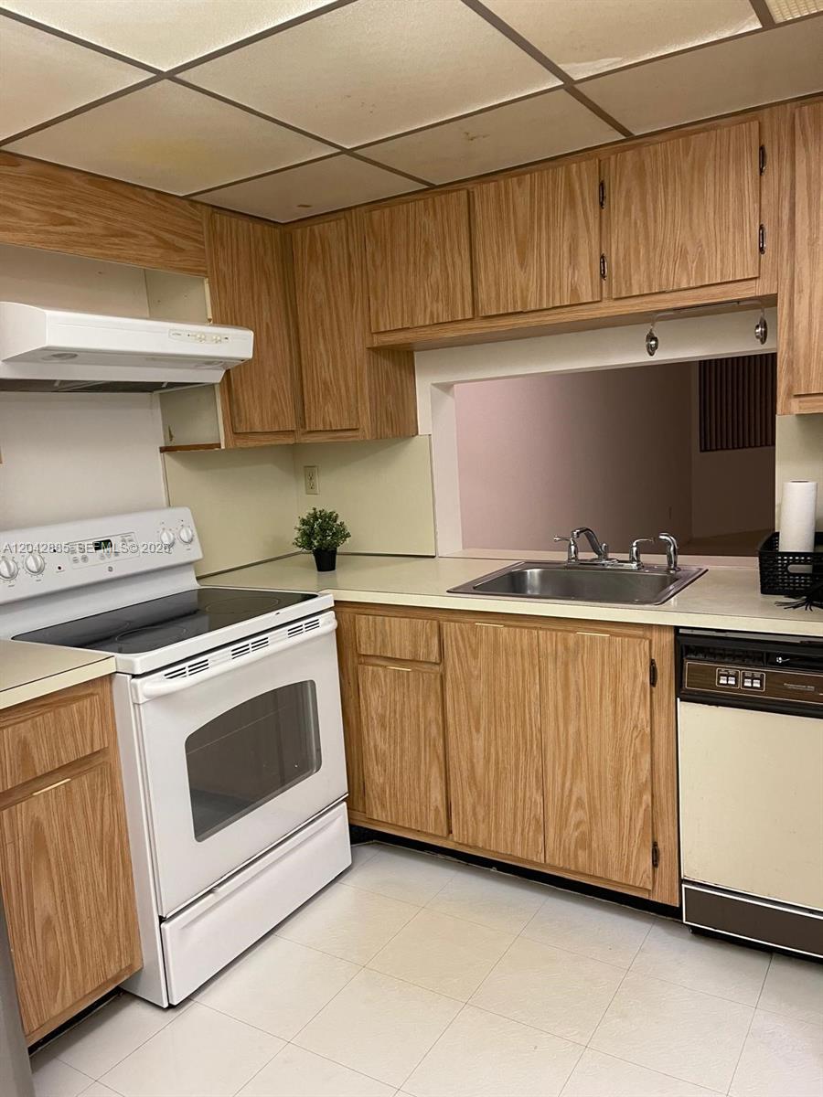 A kitchen features oak cabinets, white appliances, a stainless steel sink, and a pass-through window — 20840 San Simeon Way # 308, Miami FL 33179, MIAMI, FL
