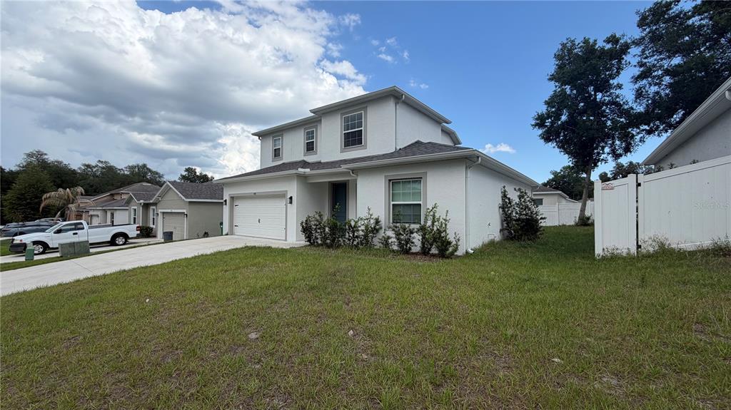 A two-story, light-colored stucco house with a garage and a white vinyl fence — 408 CIERRA OAKS CIRCLE, LADY LAKE, FL