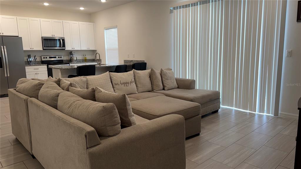 A living room with a large sectional sofa faces a kitchen with white cabinets — 408 CIERRA OAKS CIRCLE, LADY LAKE, FL