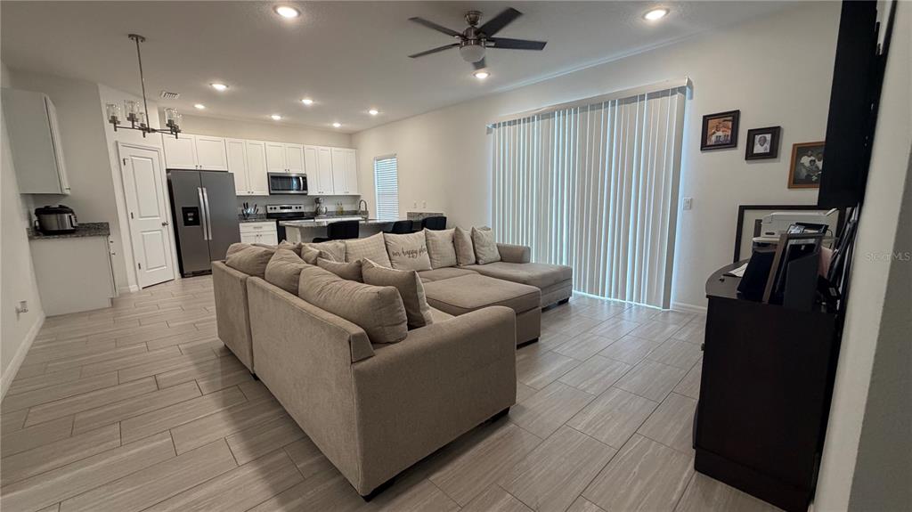 A living room with light tile floors opens to a kitchen with white cabinets — 408 CIERRA OAKS CIRCLE, LADY LAKE, FL
