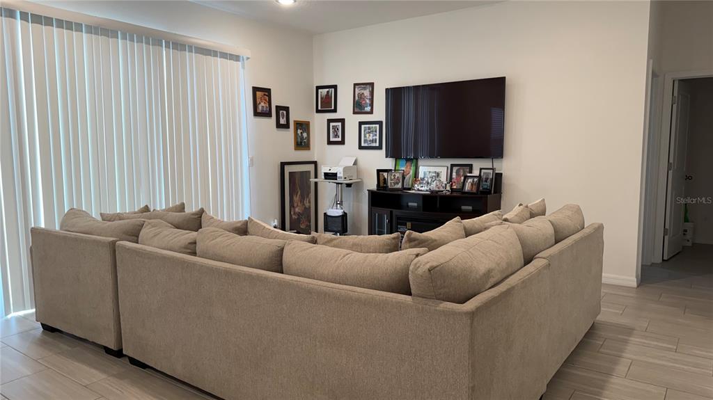 A living room features a large sectional sofa facing a television on a media console — 408 CIERRA OAKS CIRCLE, LADY LAKE, FL