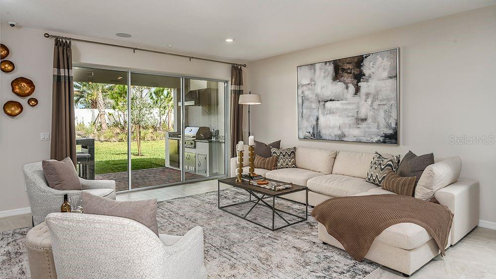 A living room features a sectional sofa, armchairs, a coffee table, and sliding glass doors — 5766 MEADS BAY POND ROAD, KISSIMMEE, FL
