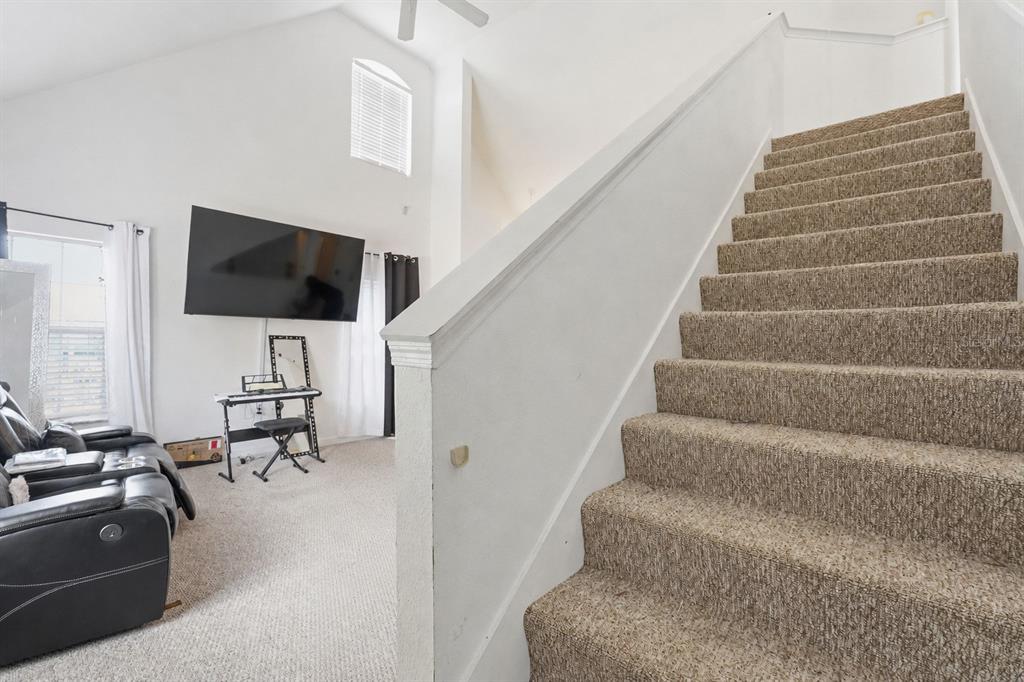A carpeted staircase leads upward next to a living area with a wall-mounted television — 10436 WHITE LAKE COURT UNIT 10436, TAMPA, FL