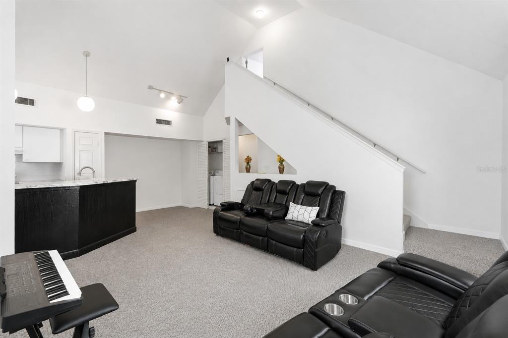 A living room with a black bar, two black leather sofas, and a staircase — 10436 WHITE LAKE COURT UNIT 10436, TAMPA, FL