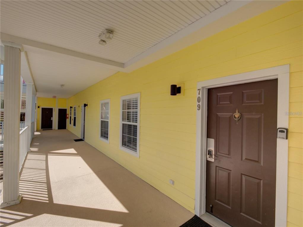 A brown front door with the number 709 sits on a yellow exterior walkway — 709 LUCAYA LOOP UNIT 1203, DAVENPORT, FL