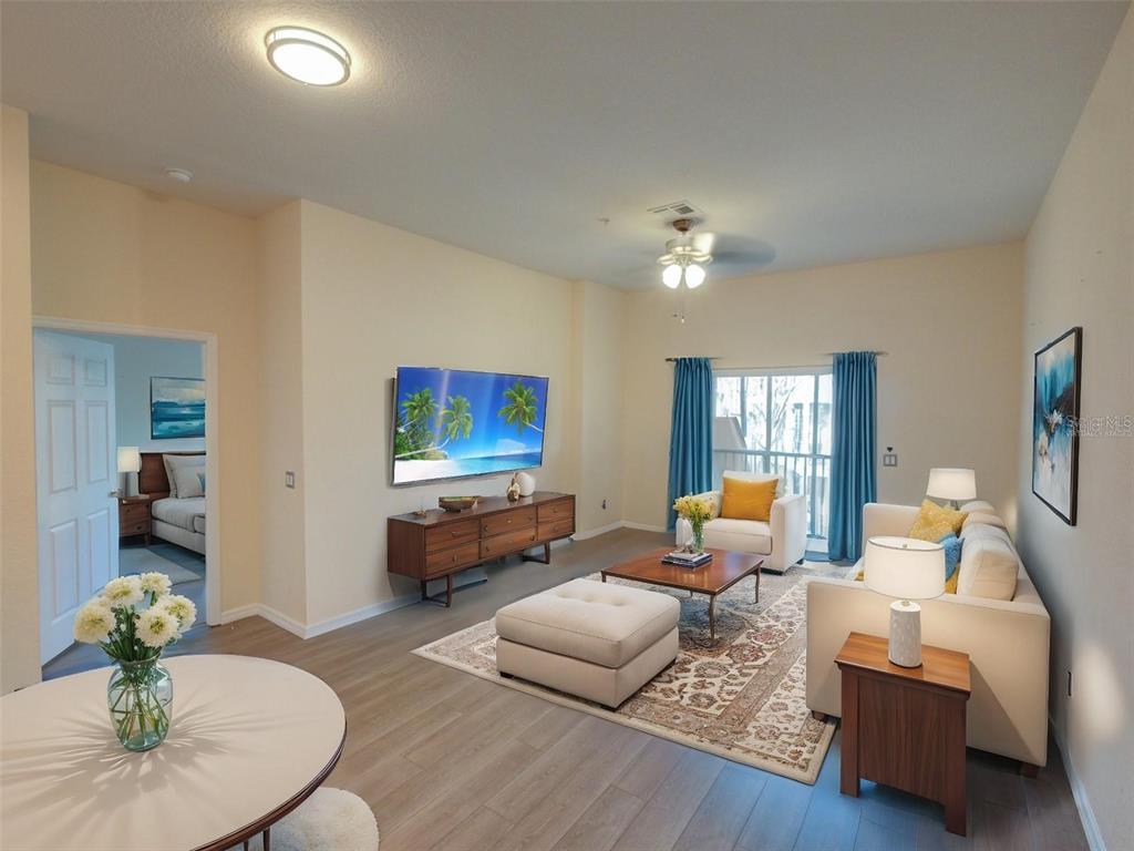 A living room features light wood flooring, a wall-mounted television, and a beige sofa — 709 LUCAYA LOOP UNIT 1203, DAVENPORT, FL