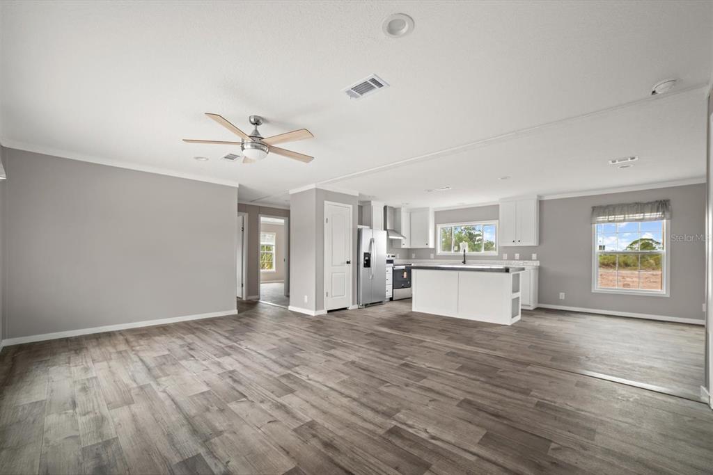 An open-concept living room and kitchen with gray walls, wood-look flooring, and white cabinetry — 20968 NW 264TH STREET, OKEECHOBEE, FL