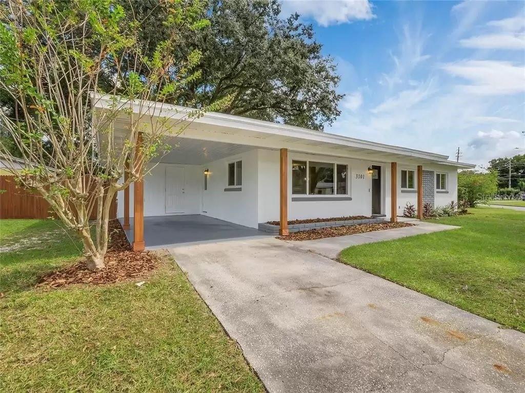 A white single-story house features a front carport with wooden posts and a concrete driveway — 3101 OXFORD STREET, ORLANDO, FL