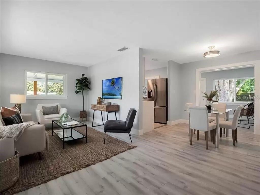 An open-concept living and dining area features light wood flooring, neutral walls, and modern furniture — 3101 OXFORD STREET, ORLANDO, FL