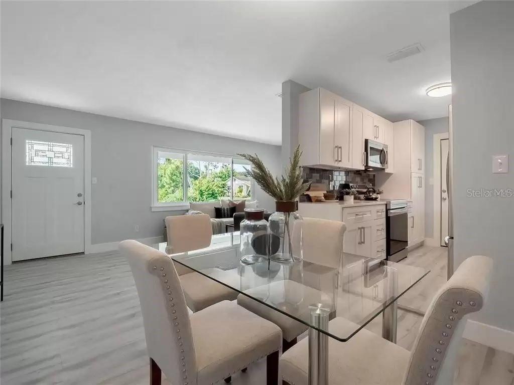 A dining area with a glass table and upholstered chairs sits adjacent to a kitchen — 3101 OXFORD STREET, ORLANDO, FL