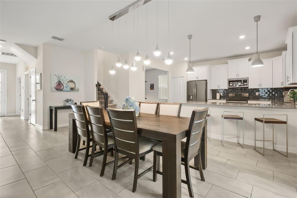 A dining area with a wooden table and chairs sits adjacent to an open kitchen — 740 DROP SHOT DRIVE, DAVENPORT, FL