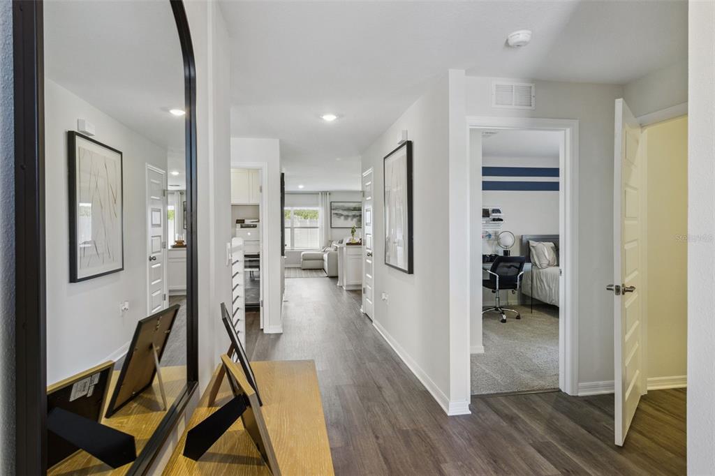 A hallway with wood-look flooring leads from a mirror-topped console table toward a living area — 2786 ADELINE AVENUE, WINTER HAVEN, FL