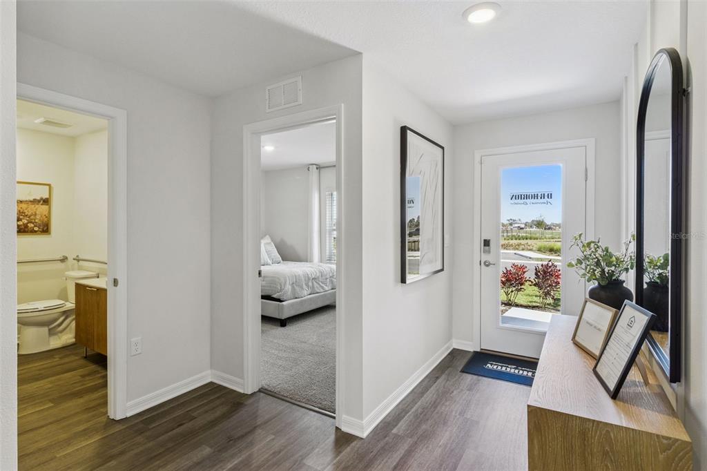 An entryway with wood-look flooring leads to a bathroom and bedroom with light gray walls — 2786 ADELINE AVENUE, WINTER HAVEN, FL