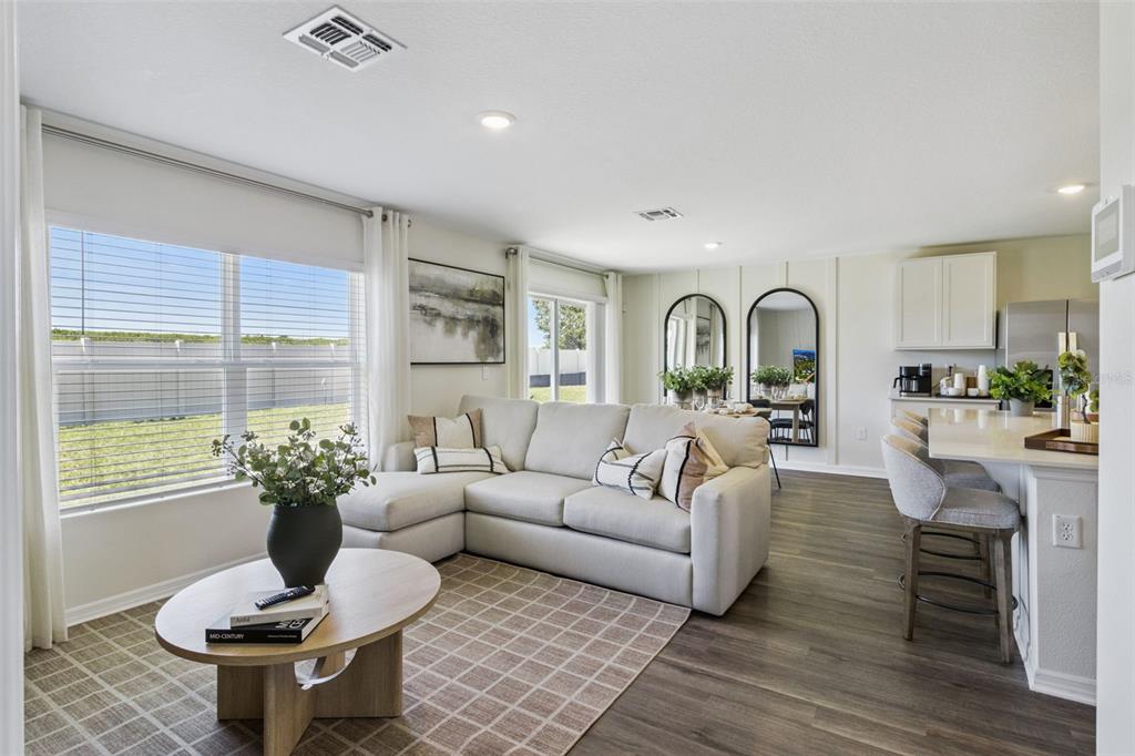 A bright living room features a sectional sofa, round coffee table, and an open kitchen — 2786 ADELINE AVENUE, WINTER HAVEN, FL