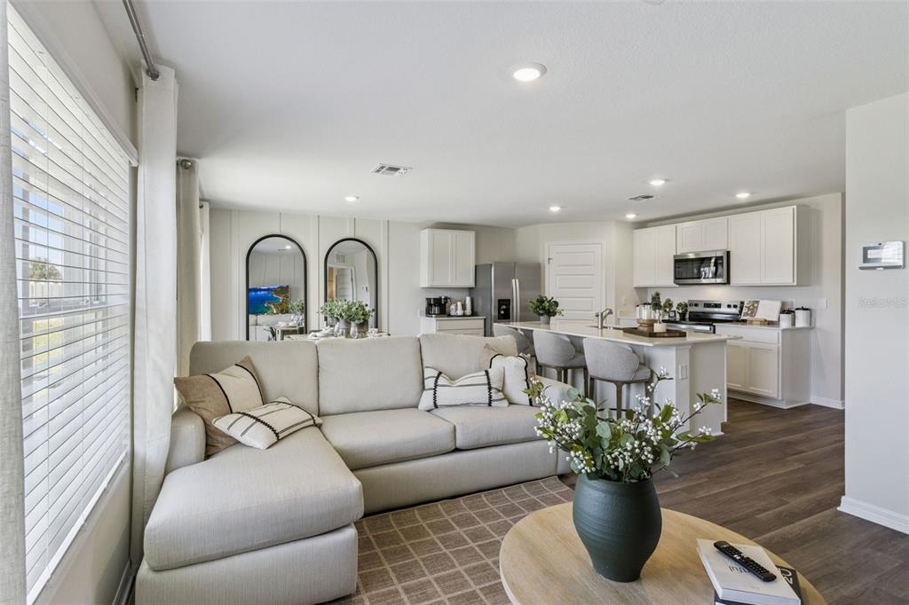 An open-concept living room and kitchen featuring a sectional sofa, island seating, and white cabinetry — 2786 ADELINE AVENUE, WINTER HAVEN, FL