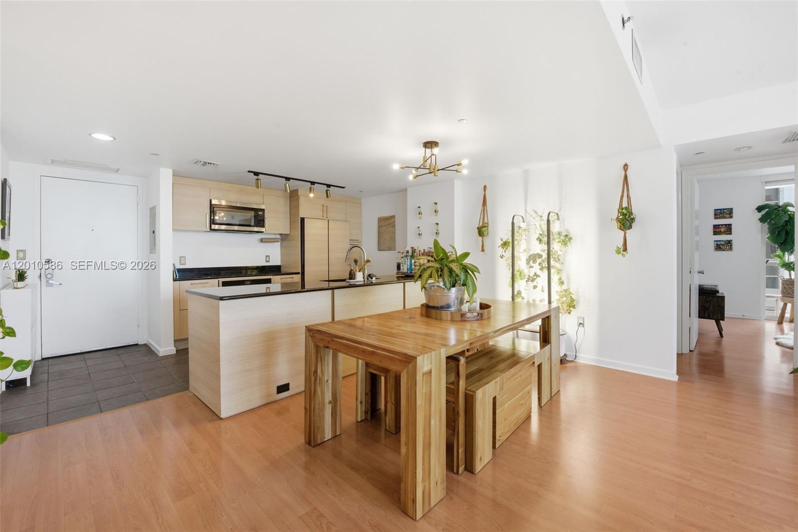 A kitchen with light wood cabinets and a wooden dining table sits in an apartment — 50 Biscayne Blvd # 2911, Miami FL 33132, MIAMI, FL