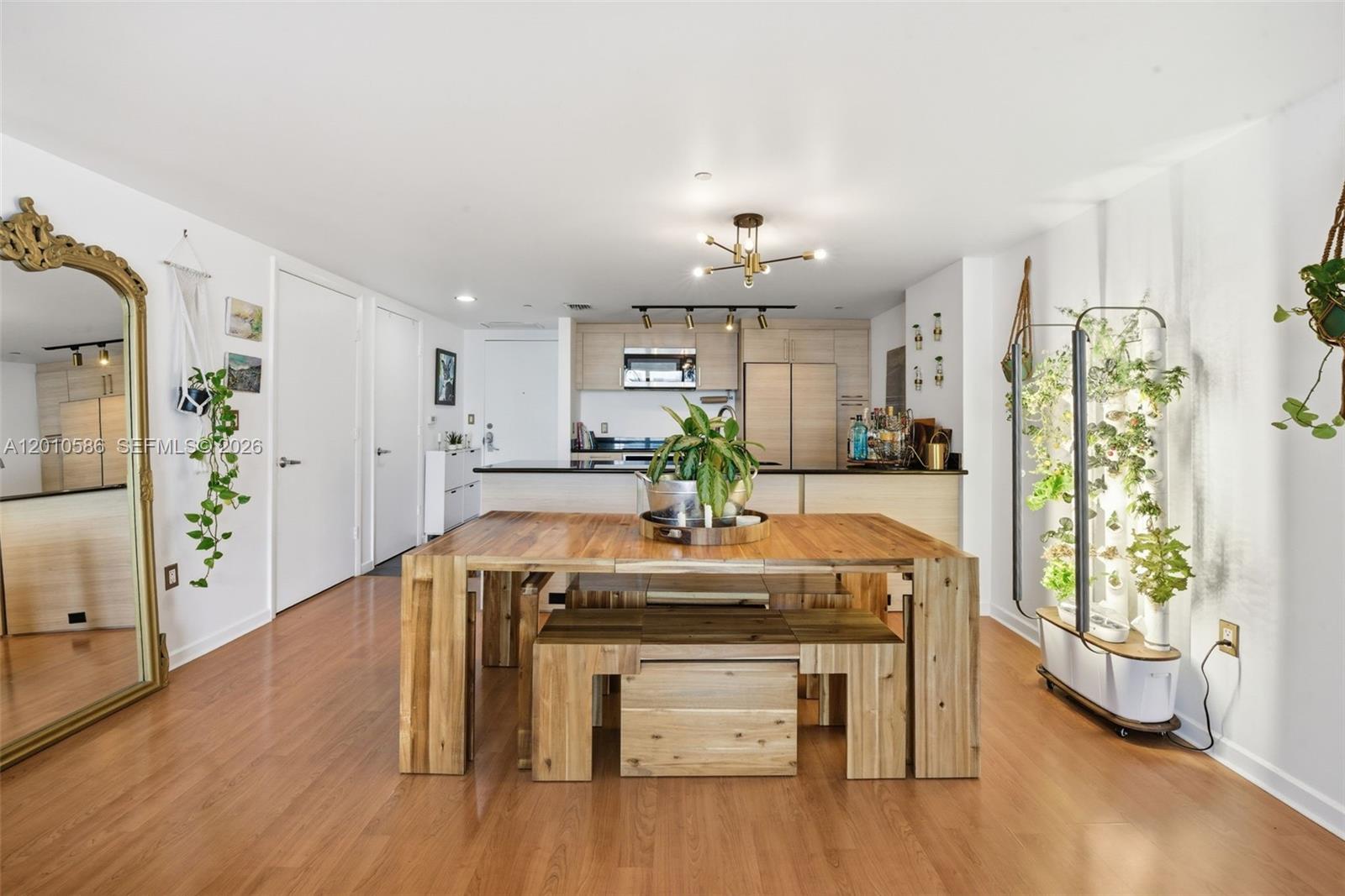 A dining area with a wooden table and benches sits in front of an open kitchen — 50 Biscayne Blvd # 2911, Miami FL 33132, MIAMI, FL