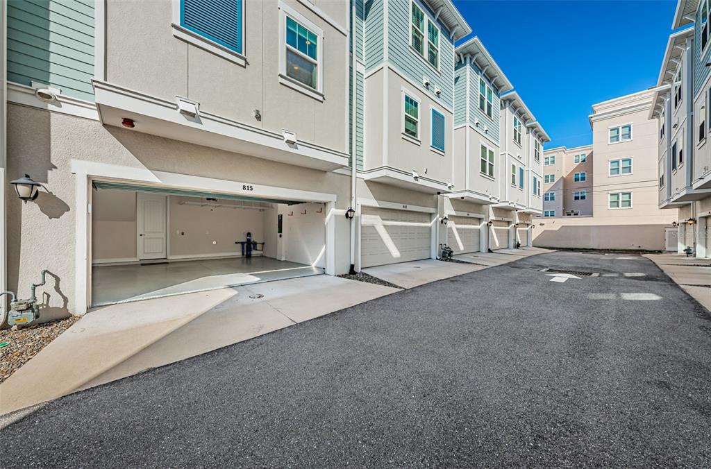 An exterior view of a row of townhomes with open garage doors and asphalt pavement — 815 BURLINGTON AVENUE N, ST PETERSBURG, FL