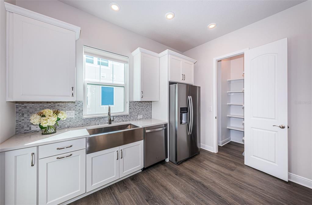 A kitchen features white cabinets, a farmhouse sink, stainless steel appliances, and a walk-in pantry — 815 BURLINGTON AVENUE N, ST PETERSBURG, FL