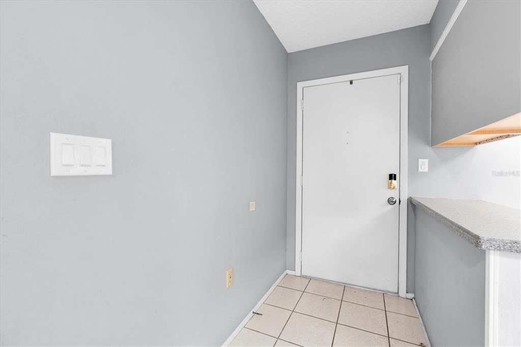 An entryway features light gray walls, a white door, and beige tiled flooring — 12227 DARWOOD DRIVE UNIT B, HUDSON, FL