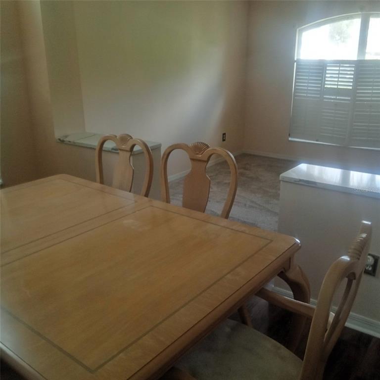 A dining room features a wooden table, chairs, and a window with plantation shutters — 15301 MONTREAT WAY, TAMPA, FL