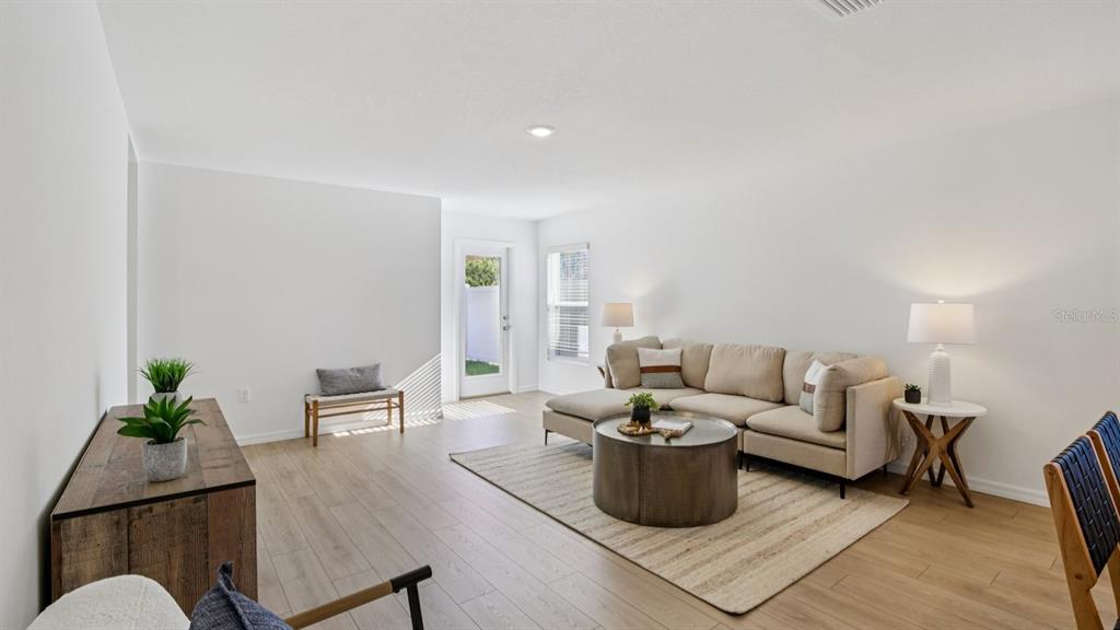 A living room features light wood-look flooring, a beige sectional sofa, and a glass door — 1207 12 STREET SE, RUSKIN, FL