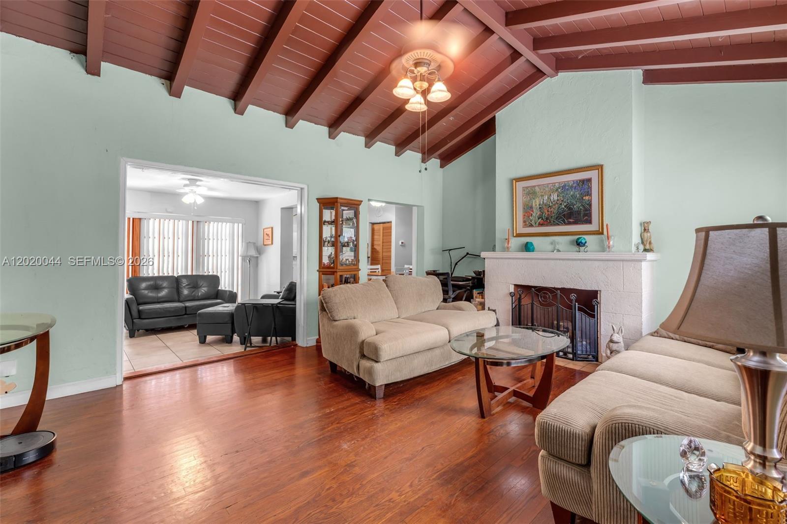 A living room features a vaulted wood-beamed ceiling, hardwood floors, and a white brick fireplace — 28 NE 48th St, Miami FL 33137, MIAMI, FL