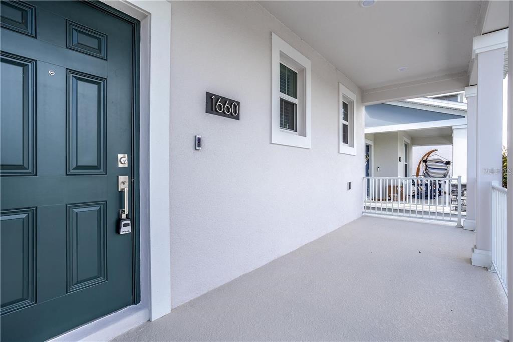 A teal front door opens onto a covered porch with white railings and stucco walls — 1660 CROSS PRAIRIE PARKWAY, KISSIMMEE, FL