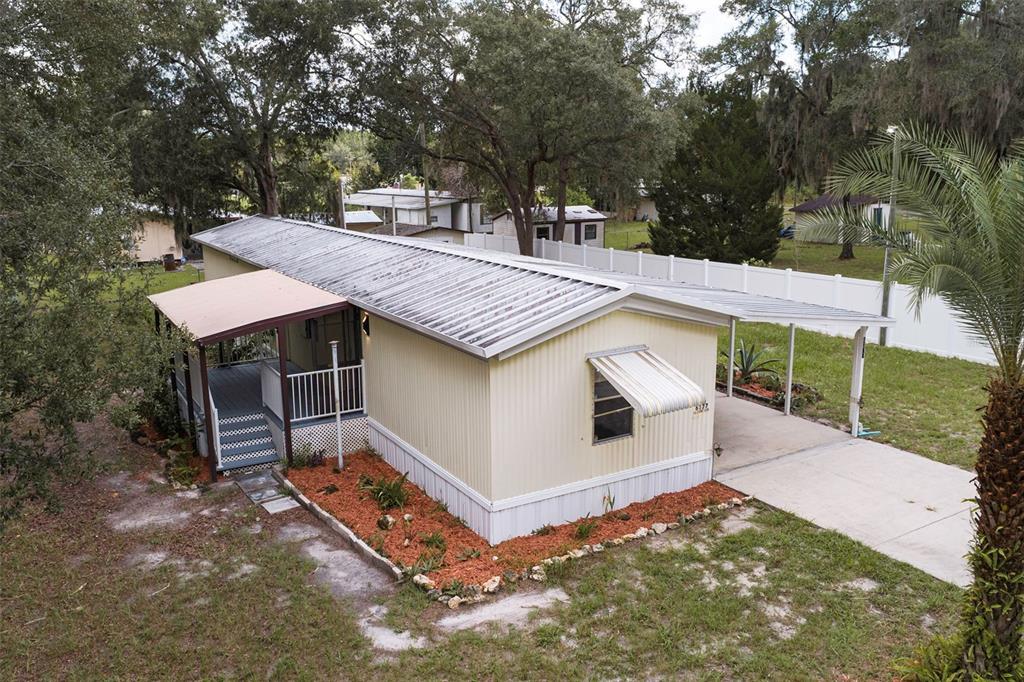 An aerial view of a single-wide mobile home with a metal roof, carport, and porch — 6377 W FLANDERS LANE, CRYSTAL RIVER, FL