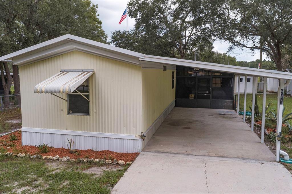 A light yellow mobile home with a metal awning, a carport, and a screened-in entrance — 6377 W FLANDERS LANE, CRYSTAL RIVER, FL