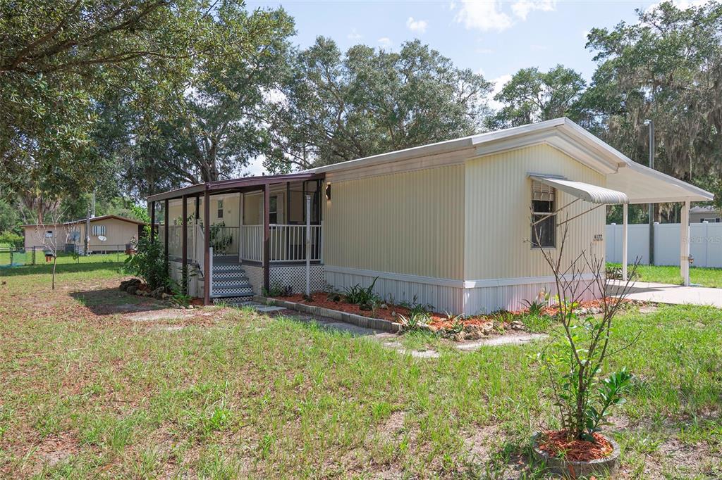 A light yellow mobile home features a covered front porch and an attached carport — 6377 W FLANDERS LANE, CRYSTAL RIVER, FL