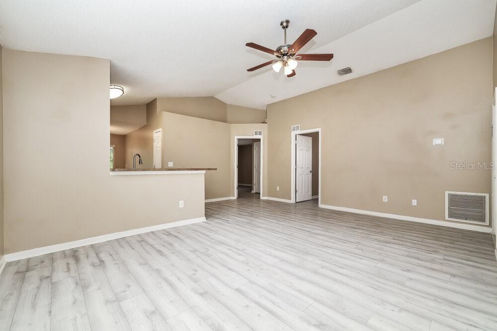 An empty living room with light wood-look flooring, beige walls, and a ceiling fan — 6719 SUMMER COVE DRIVE, RIVERVIEW, FL