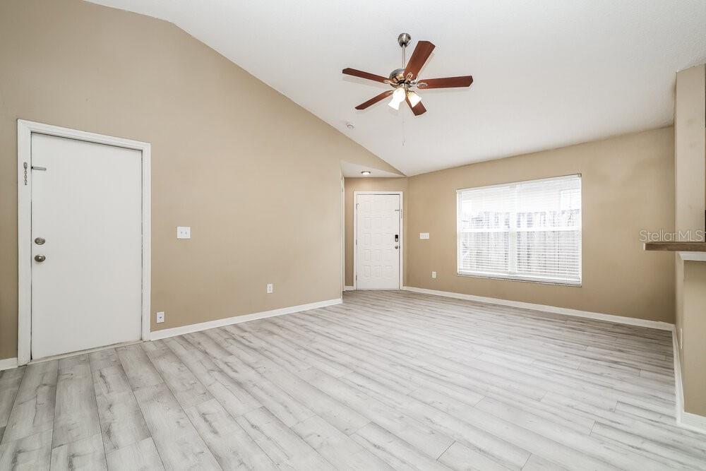 A living room with light wood-look flooring, beige walls, a vaulted ceiling, and a ceiling fan — 6719 SUMMER COVE DRIVE, RIVERVIEW, FL